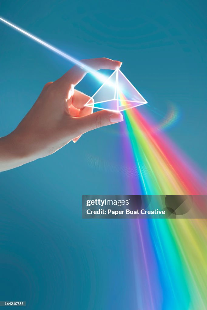 Hand holding rainbow light prism in studio