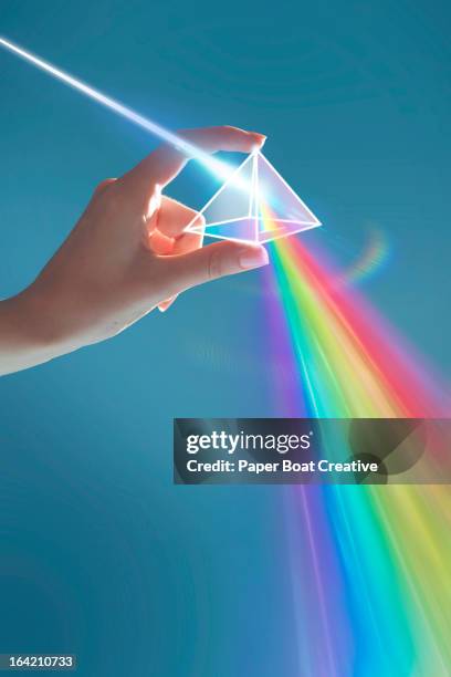 hand holding rainbow light prism in studio - prisma stockfoto's en -beelden