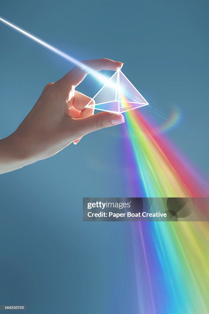 Hand holding rainbow light prism in studio