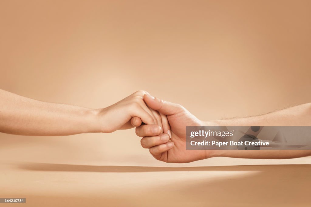 Close up of man and woman holding hands in studio