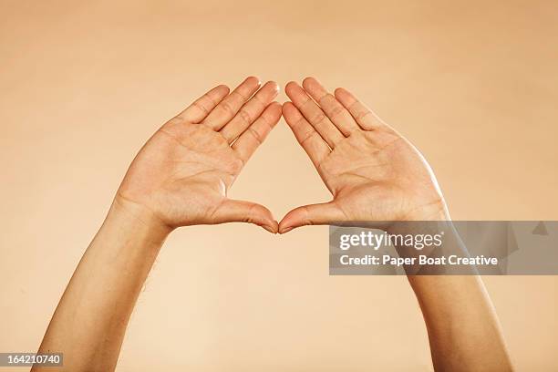 hands making triangle formation plain background - dreiecke stock-fotos und bilder