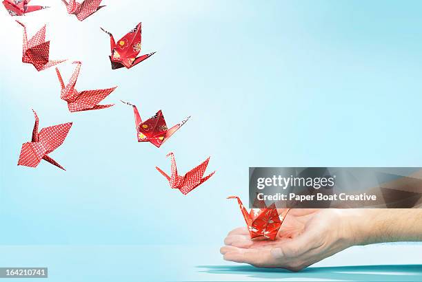 red origami cranes flying away from hands - grou pássaro - fotografias e filmes do acervo