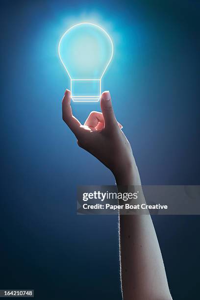 hand holding glowing light bulb studio background - hände glühlampe stock-fotos und bilder