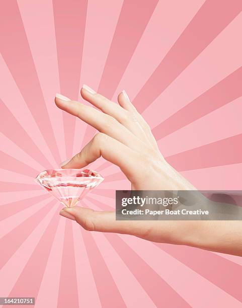 hand holding pink diamond with pink background - pink diamond stock pictures, royalty-free photos & images