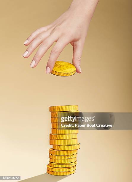 hand putting paper gold coin on stack of coins - positionner photos et images de collection