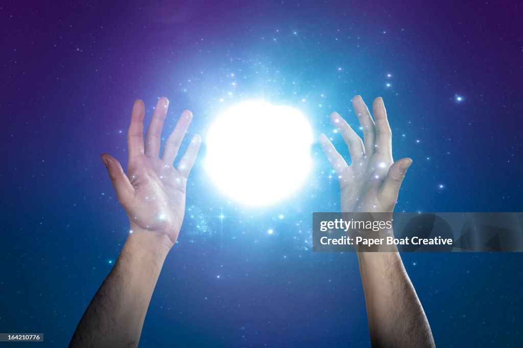 Hand supporting abstract glow of light and stars