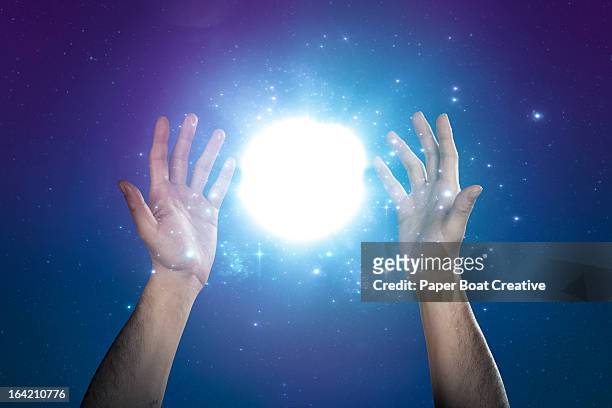 hand supporting abstract glow of light and stars - übersinnliches stock-fotos und bilder