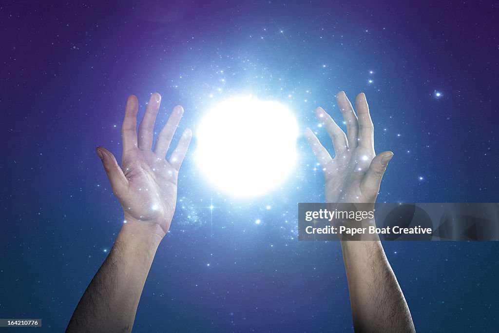 Hand supporting abstract glow of light and stars