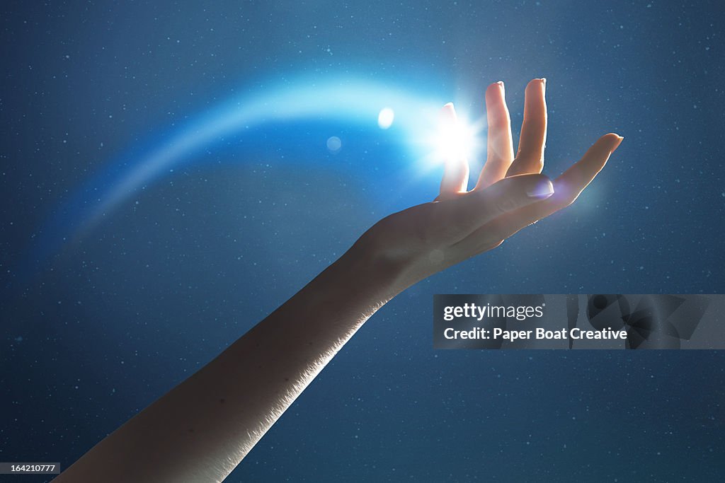 Hand holding a glowing shooting star