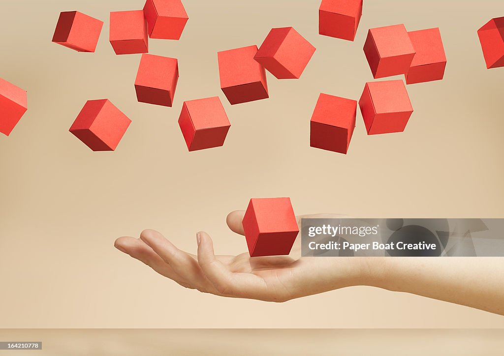 Hand holding floating paper boxes in the studio