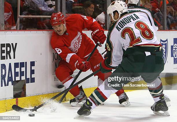 Ian White of the Detroit Red Wings and Zenon Konopka of the Minnesota Wild battle for the puck in NHL action at Joe Louis Arena on March 20, 2013 in...