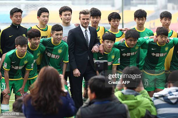 Football superstar David Beckham poses for a photo with fans and players during a visit to Beijing Guoan soccer club in Beijing on March 21, 2013....