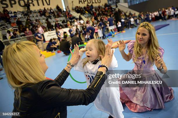 Child with Down Syndrome claps hands with her mother during an event marking the International Day of Down Syndrome in Bucharest March 21, 2013....