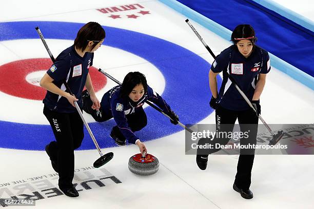 Satsuki Fujisawa of Japan throws the stone as Emi Shimizu and Chiaki Matsumura sweep in the match between Japan and Sweden on Day 5 of the Titlis...