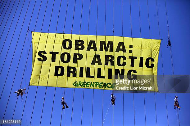Greenpeace activists hang a banner saying 'Obama Stop Arctic drilling' on the cables of Jerusalem's Chords Bridge on March 21, 2013 in Jerusalem,...
