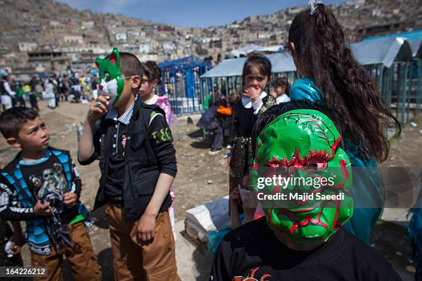 An Afghan boy wears a mask as he plays near the Sakhi shrine, which is the centre of the Afghanistan new year celebrations during the Nowruz...