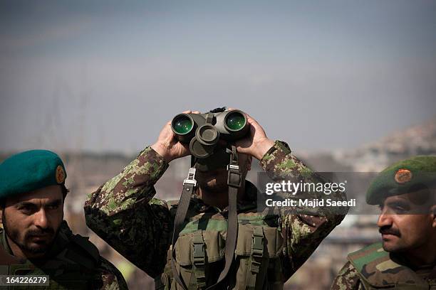 An Afghan soldier keeps watch using his binoculars near the Sakhi shrine, which is the centre of the Afghanistan new year celebrations during the...