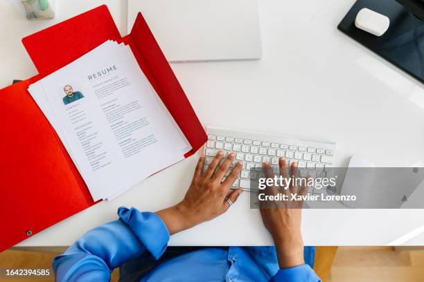 top view of hr manager desktop with job applicant's resume inside a red folder while typing on keyboard. recruitment human resources employment hiring concept. - cv bildbanksfoton och bilder