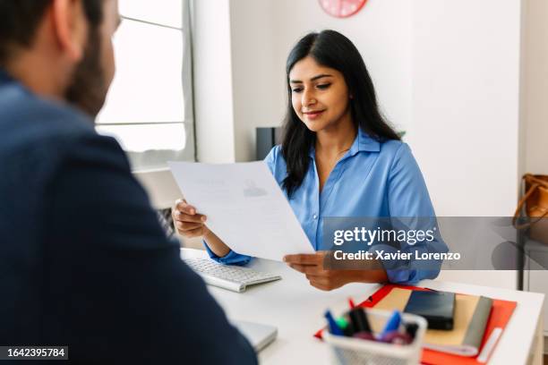 professional indian female recruiter manager reading candidate’s resume while doing a job interview in a modern office. recruitment human resources employment hiring concept. - entrevista imagens e fotografias de stock
