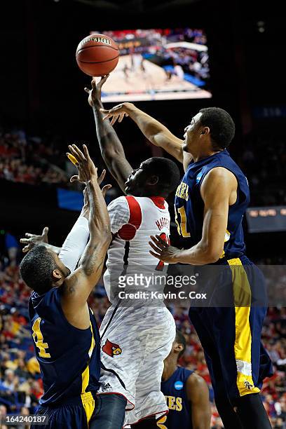 Stephan Van Treese of the Louisville Cardinals shoots the ball against DaMetrius Upchurch and Austin Witter of the North Carolina A&T Aggies during...