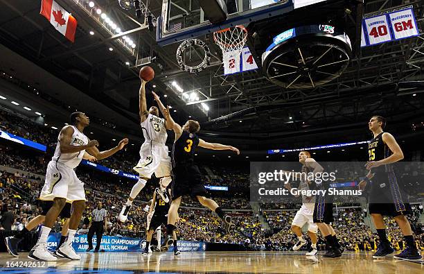 Trey Burke of the Michigan Wolverines drives for a shot attempt against Nate Wolters of the South Dakota State Jackrabbits during the second round of...