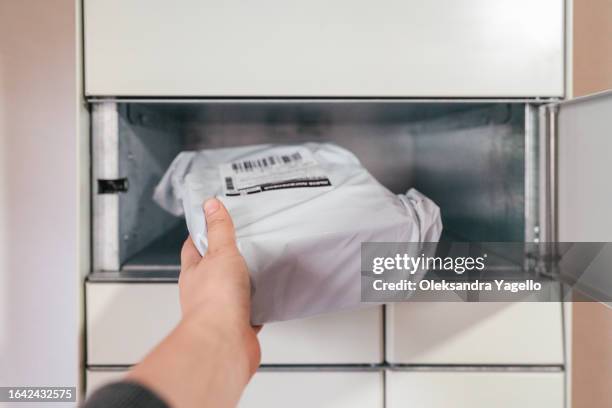 parcel in hand on the background of a open terminal machine. automatic parcel delivery service. self-service storage locker. - ranura de buzón fotografías e imágenes de stock