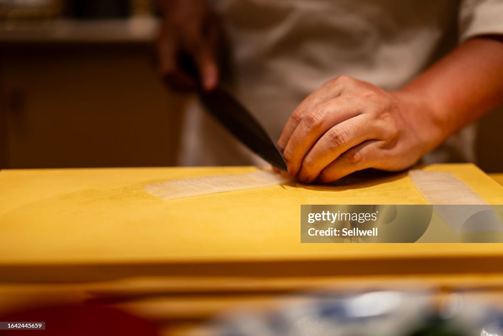 Close up of chef cutting sashimi on kitchen board