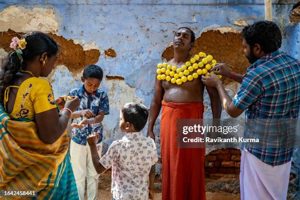 a devotee getting lemons stitched to his body while his family is helping him - kaveripattinam stock pictures, royalty-free photos & images