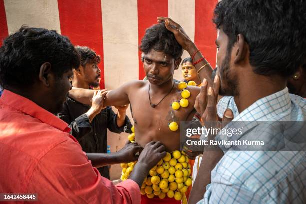 a devotee in pain held by his family members while getting lemons stictched to his bbody. - kaveripattinam stock pictures, royalty-free photos & images