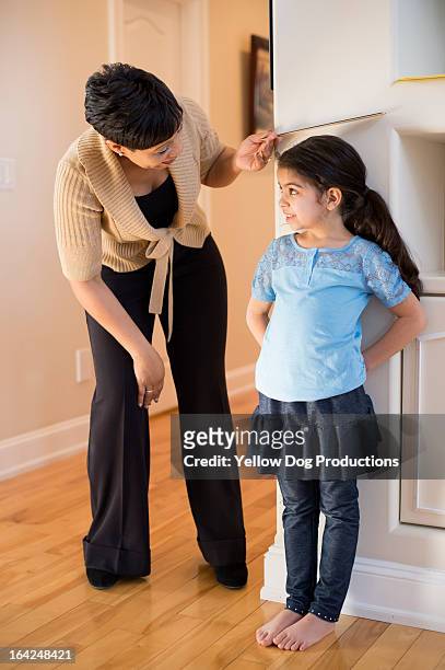 mom measuring daughter's height against wall - child's wall height stock-fotos und bilder