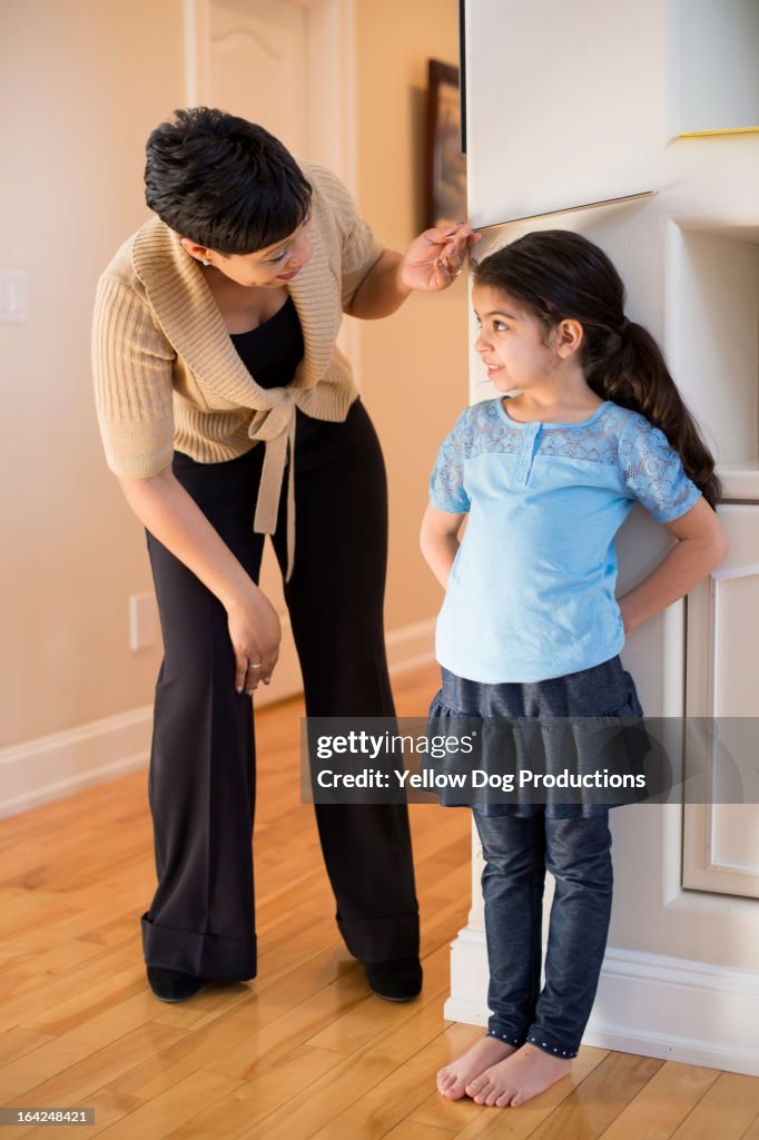 Mom measuring daughter's height against wall