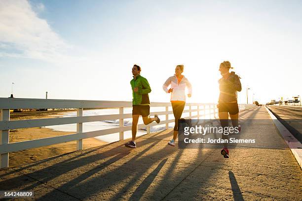 jogging along the coast. - beach sports stock-fotos und bilder