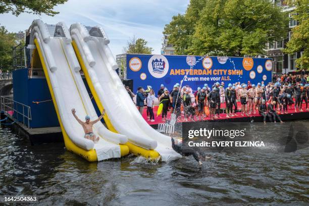 Participants of the "Amsterdam City Swim" event slide down a waterslide into the Keizersgracht canal in Amsterdam, The Netherlands, on September 3,...