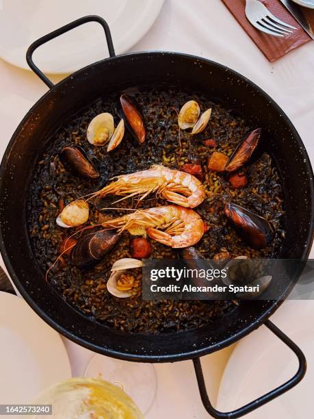 paella with black rice and seafood served in a restaurant, spain - black rice stock pictures, royalty-free photos & images