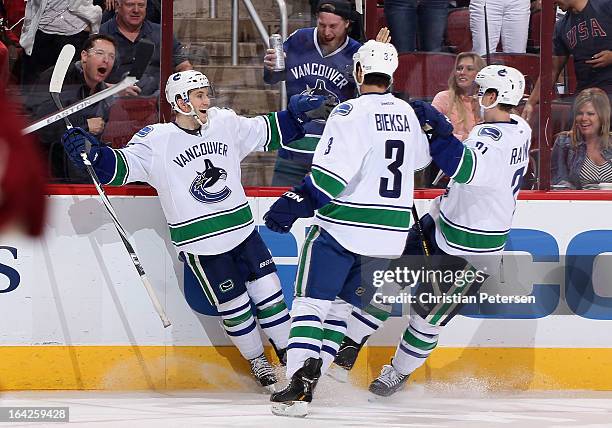 Jordan Schroeder of the Vancouver Canucks celebrates with Kevin Bieksa and Mason Raymond after Schroeder scored a third period goal against the...