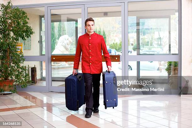 bellhop carrying luggage - piccolo stockfoto's en -beelden