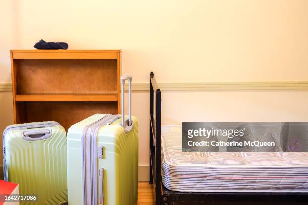 view into student dorm room on move in day (suitcases, bed, bookshelf, hat in view) - boarding school bildbanksfoton och bilder