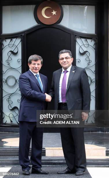 Turkish Foreign minister Ahmet Davutoglu shakes hands with Syrian opposition prime minister Ghassan Hitto prior to a meeting in Ankara, on March 22,...