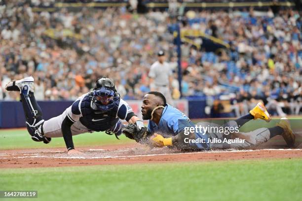 Randy Arozarena of the Tampa Bay Rays slides in to score against Kyle Higashioka of the New York Yankees on a throwing error by Harrison Bader of the...