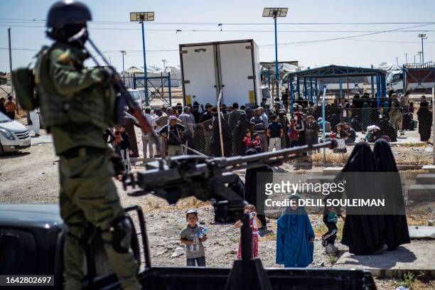 Member of Kurdish security forces stands guard as released detainees prepare to leave the Kurdish-run al-Hol camp, which holds relatives of suspected...