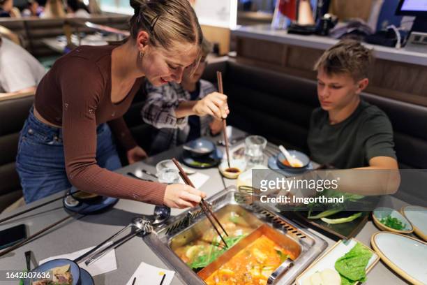 three teenagers having hot pot lunch in an asian restaurant - soup bowl stock pictures, royalty-free photos & images
