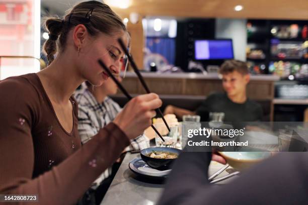 mother and three teenagers having hot pot lunch in an asian restaurant - trying new food stock pictures, royalty-free photos & images