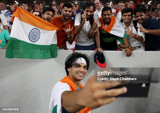 Gold medalist Neeraj Chopra of Team India celebrates winning by taking selfies with fans after the Men's Javelin Throw Final during day nine of the...
