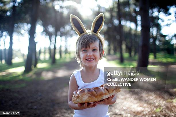 boy in easter bunny ears with hot cross buns - hot cross bun stock pictures, royalty-free photos & images