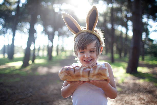 boy in easter bunny ears with hot cross buns - easter australia hot cross buns stock pictures, royalty-free photos & images