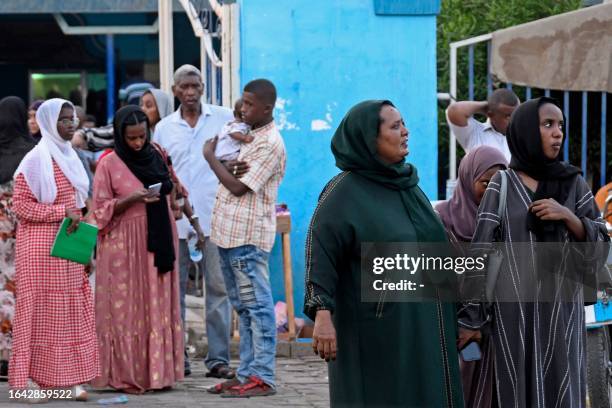 Sudanese wait outside a Passports and Immigration Services office in Port Sudan on September 3 following an announcement by the authorities of the...