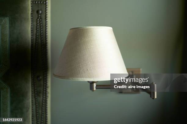 a beige lamp attached to the wall with bronze-colored tubes and a dark green background. - abajur imagens e fotografias de stock