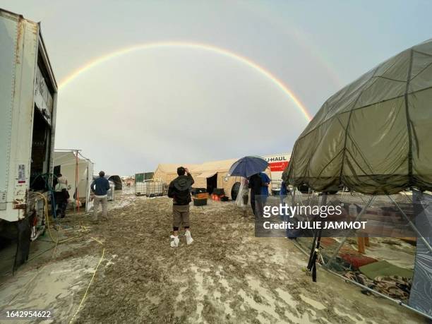 Attendees look at a rainbow over flooding on a desert plain on September 1 after heavy rains turned the annual Burning Man festival site in Nevada's...