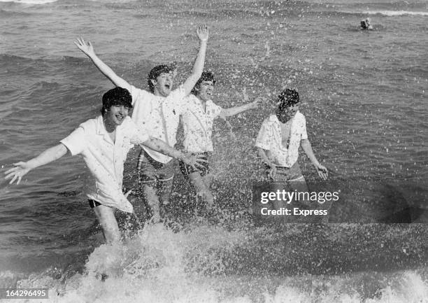 English pop group The Beatles frolicking in the surf at Miami Beach, Florida, February 1964. Left to right: John Lennon , Paul McCartney, George...