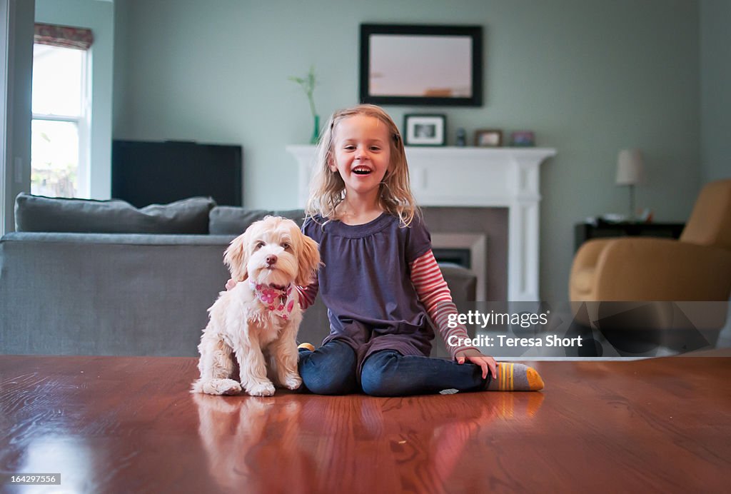 Girl and Puppy Sitting on Floor Together